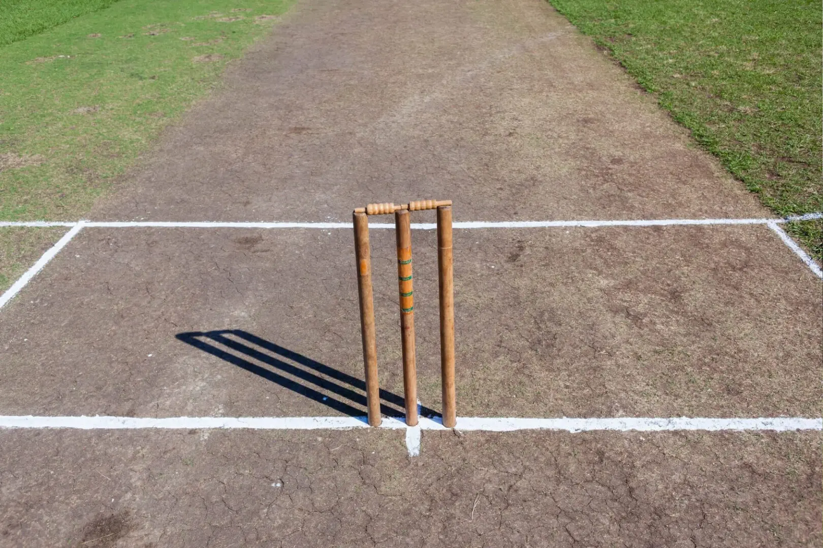 A cricket field with two wooden wickets on the side.