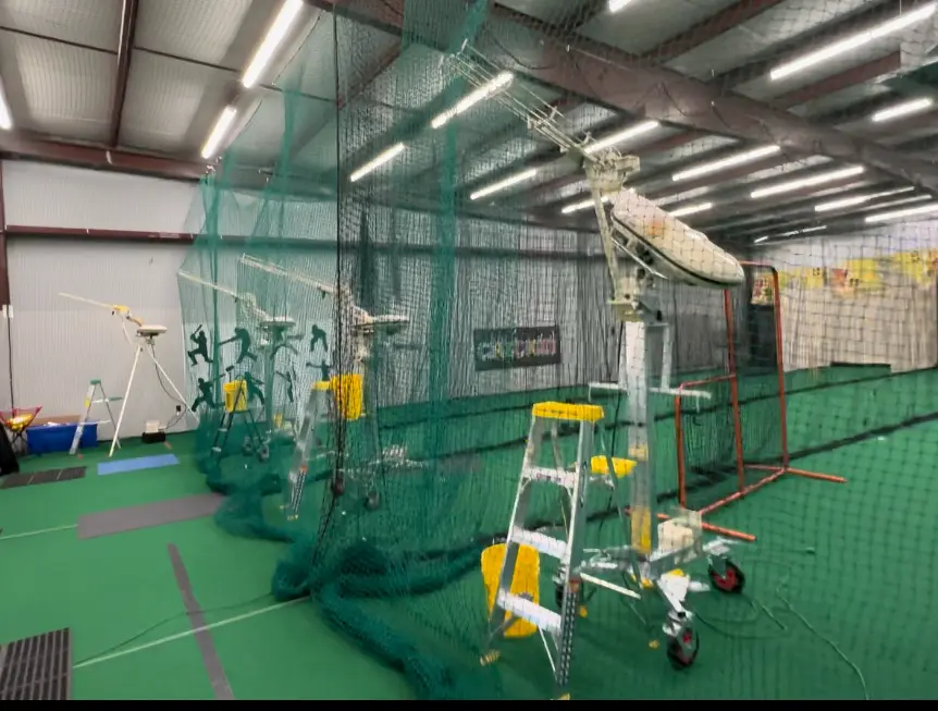 Indoor facility with green indoor turf and multiple bowling machines.