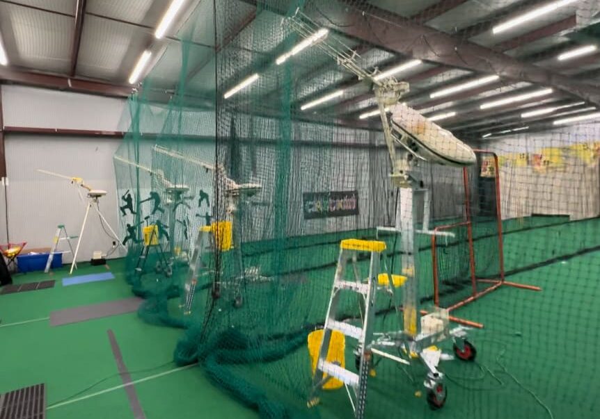 Indoor facility with green indoor turf and multiple bowling machines.